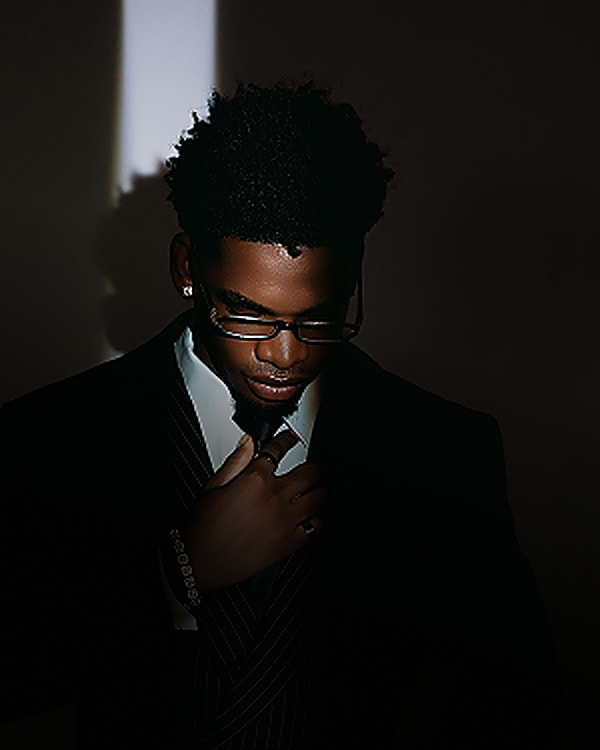 Man in a suit adjusting his tie in low light