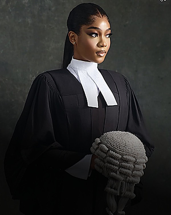 Woman in a barrister's gown and bib holding a wig